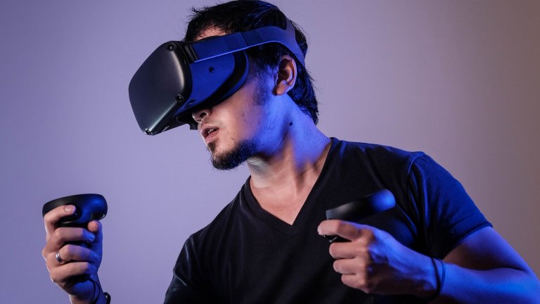 Mann im schwarzen T-Shirt trägt VR-Brille und hält schwarzes Smartphone in der Hand